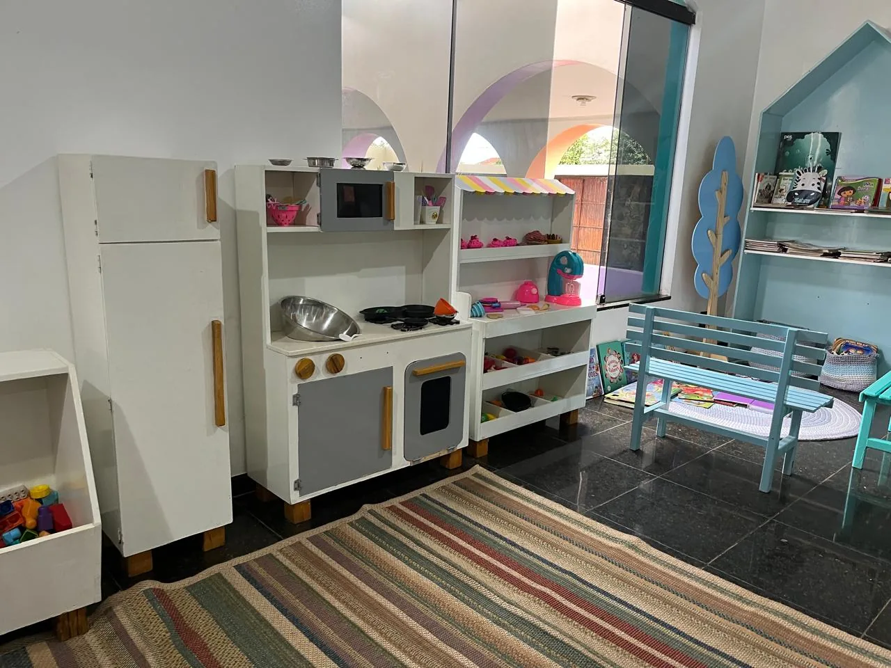 Brinquedoteca com cozinha de faz de conta, livros e mobiliário infantil
