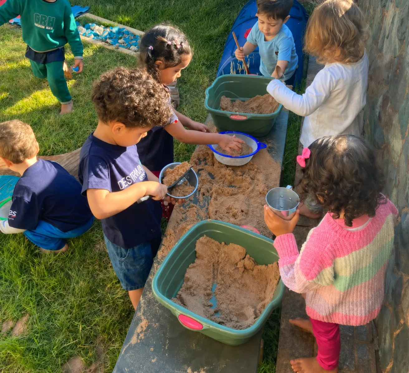 Crianças explorando terra, areia e utensílios em proposta de Mud Kitchen